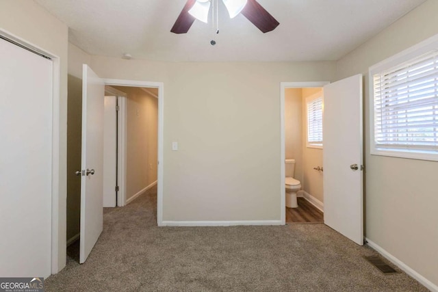 unfurnished bedroom with a closet, light colored carpet, ensuite bath, and ceiling fan