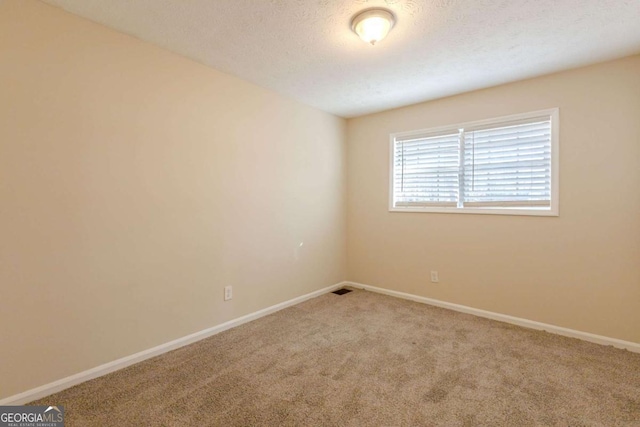 carpeted empty room featuring a textured ceiling