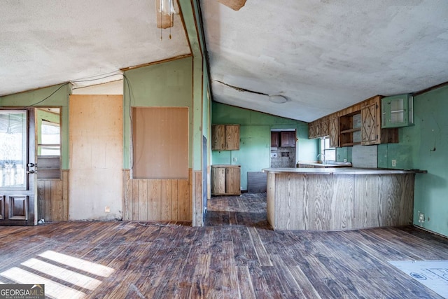 kitchen with green cabinetry, kitchen peninsula, dark wood-type flooring, and vaulted ceiling