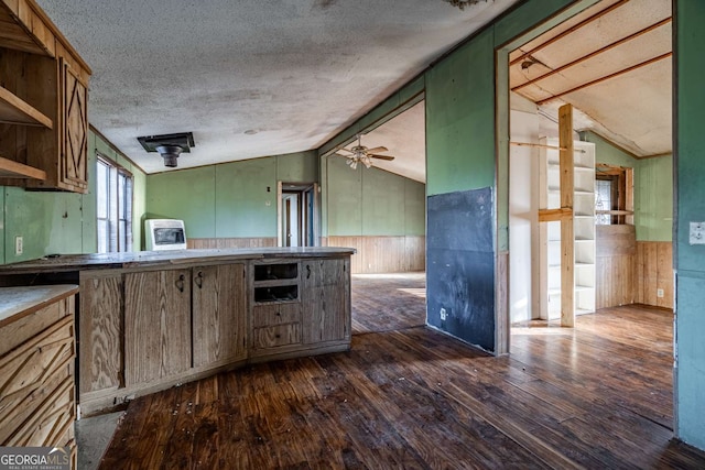 kitchen featuring a textured ceiling, ceiling fan, dark hardwood / wood-style floors, lofted ceiling, and wood walls