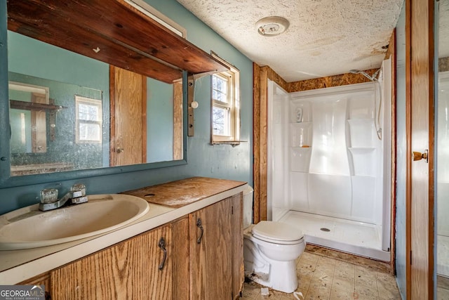 bathroom with a shower, vanity, a textured ceiling, and toilet