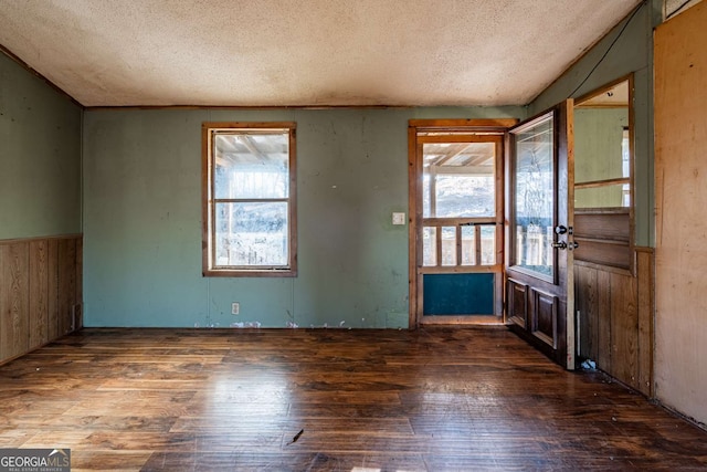 entryway with a textured ceiling, dark hardwood / wood-style flooring, and wood walls