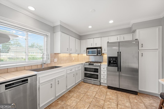 kitchen featuring light tile patterned flooring, stainless steel appliances, white cabinetry, and sink