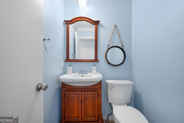 bathroom with vanity, toilet, and ornamental molding