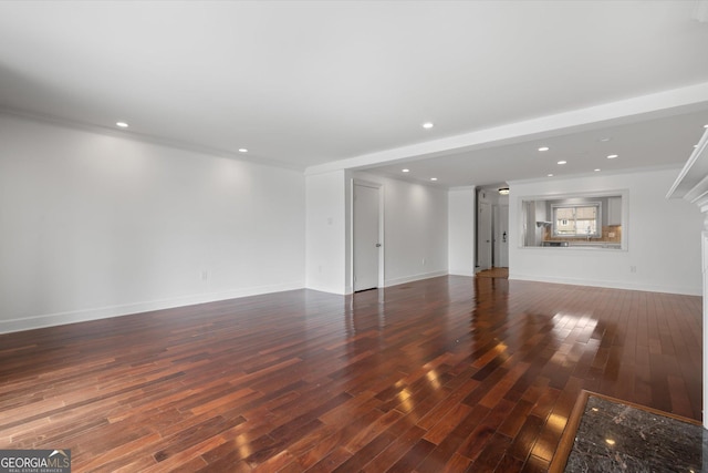 unfurnished living room with ornamental molding and dark wood-type flooring