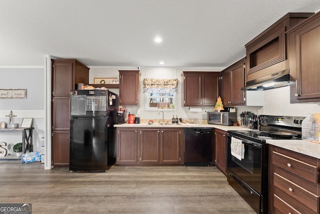 kitchen with dark brown cabinetry, sink, black appliances, exhaust hood, and light wood-type flooring