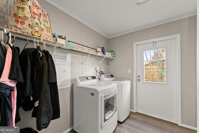 clothes washing area with washing machine and clothes dryer and light hardwood / wood-style floors