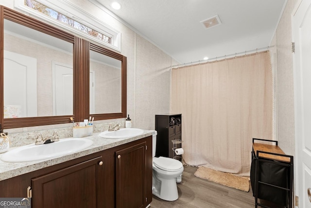 bathroom featuring vanity, crown molding, hardwood / wood-style flooring, toilet, and walk in shower