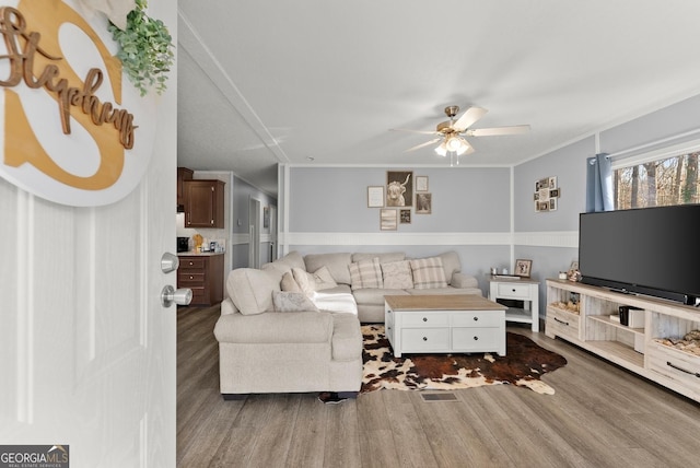 living room with hardwood / wood-style flooring, ceiling fan, and crown molding