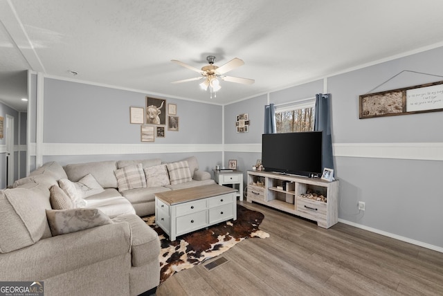 living room featuring hardwood / wood-style floors, ceiling fan, crown molding, and a textured ceiling