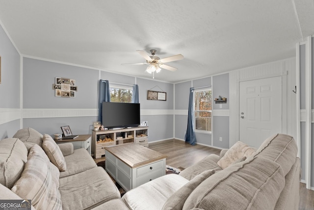 living room featuring light wood-type flooring, a wealth of natural light, ornamental molding, and ceiling fan