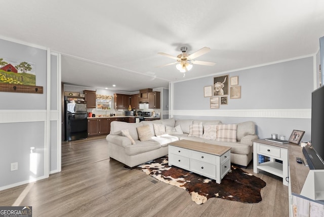 living room with ceiling fan, ornamental molding, and light wood-type flooring