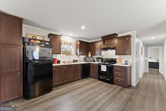 kitchen with sink, extractor fan, light hardwood / wood-style floors, black appliances, and ornamental molding