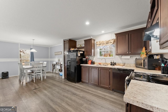 kitchen with sink, pendant lighting, black appliances, dark brown cabinets, and exhaust hood