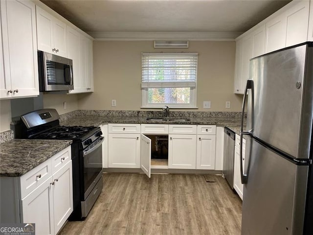 kitchen with sink, stainless steel appliances, dark stone countertops, white cabinets, and ornamental molding