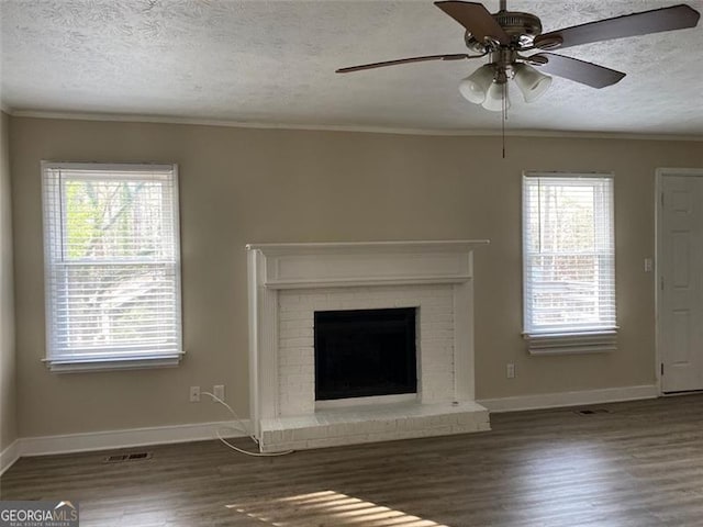 unfurnished living room with ceiling fan, ornamental molding, a textured ceiling, a fireplace, and dark hardwood / wood-style flooring