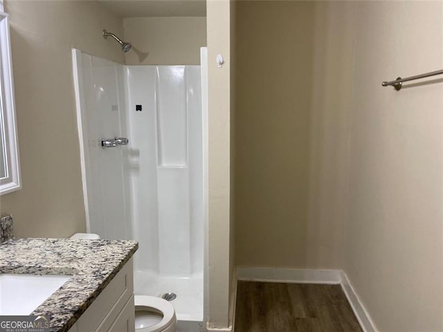 bathroom with hardwood / wood-style floors, vanity, toilet, and walk in shower