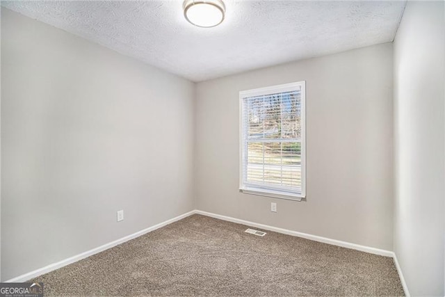 carpeted empty room with a textured ceiling