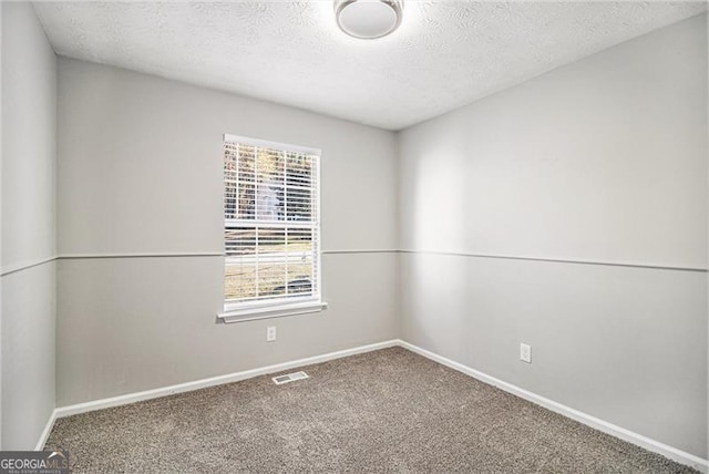 carpeted spare room with a textured ceiling