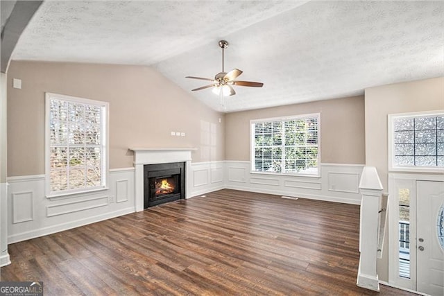 unfurnished living room with a textured ceiling, vaulted ceiling, ceiling fan, and dark wood-type flooring