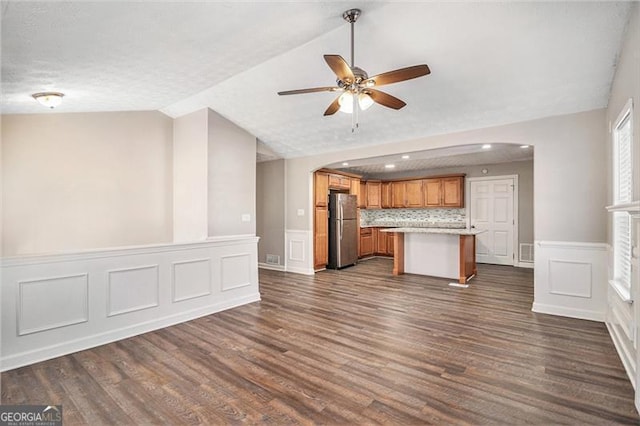 kitchen featuring stainless steel fridge, dark hardwood / wood-style flooring, vaulted ceiling, ceiling fan, and a kitchen island