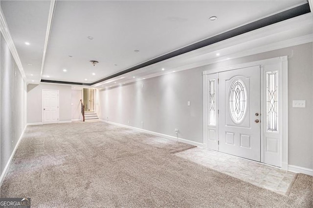 foyer entrance with carpet floors, a tray ceiling, and ornamental molding