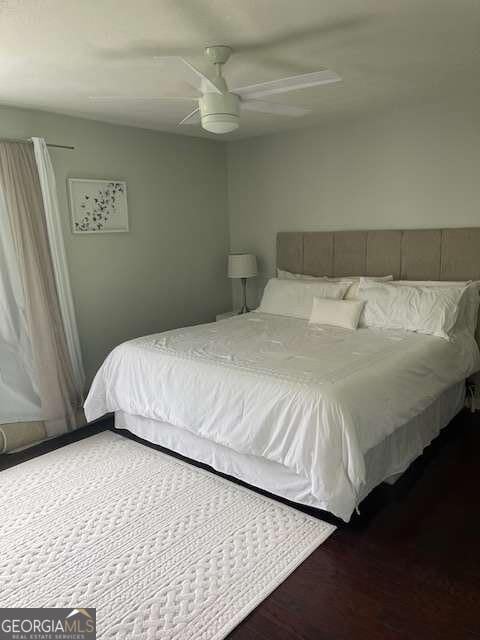 bedroom with dark hardwood / wood-style flooring and ceiling fan