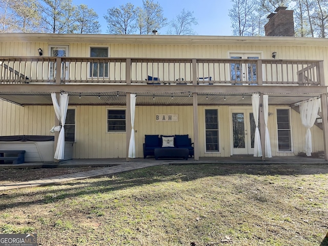 rear view of house featuring a yard, a hot tub, and a deck