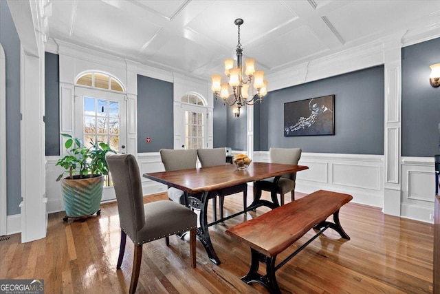 dining room with wood-type flooring, a notable chandelier, crown molding, and coffered ceiling