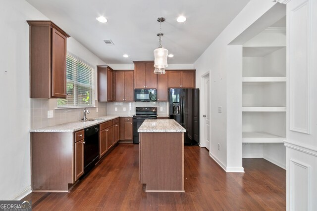 kitchen featuring light stone countertops, sink, hanging light fixtures, a kitchen island, and black appliances