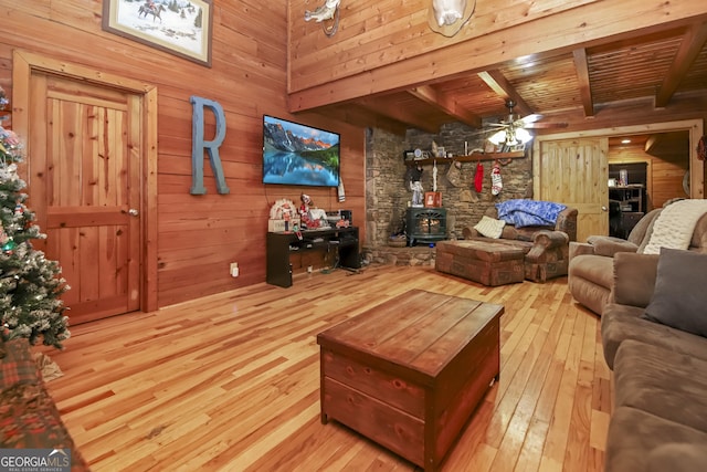 living room with a wood stove, ceiling fan, beam ceiling, wood-type flooring, and wood ceiling