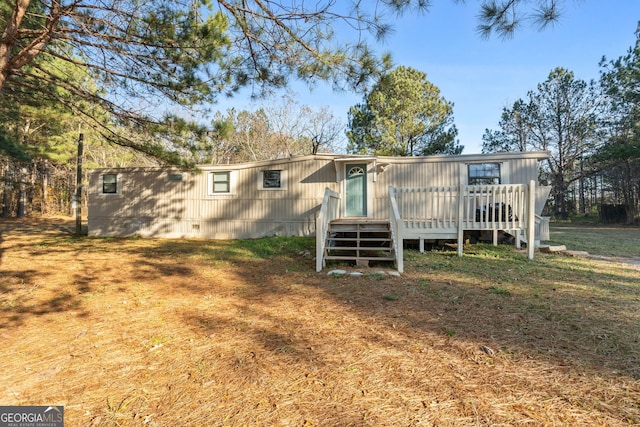 back of property with a lawn and a wooden deck