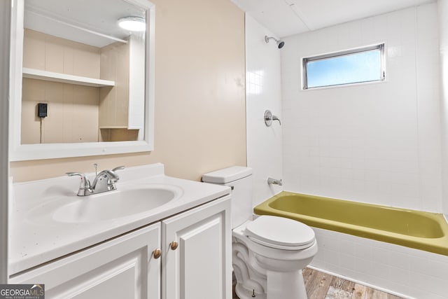 full bathroom with tiled shower / bath, vanity, wood-type flooring, and toilet