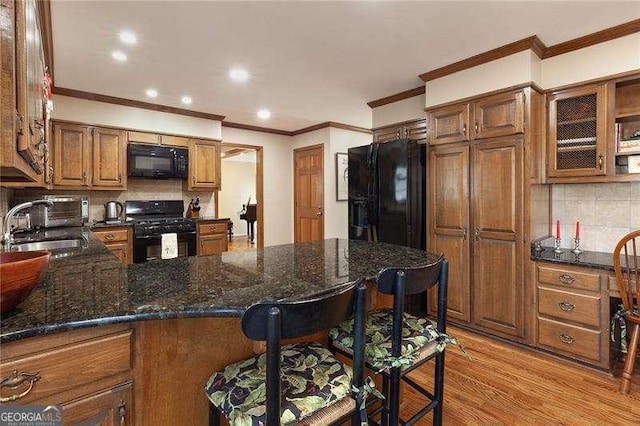 kitchen featuring a breakfast bar, black appliances, sink, light hardwood / wood-style flooring, and kitchen peninsula