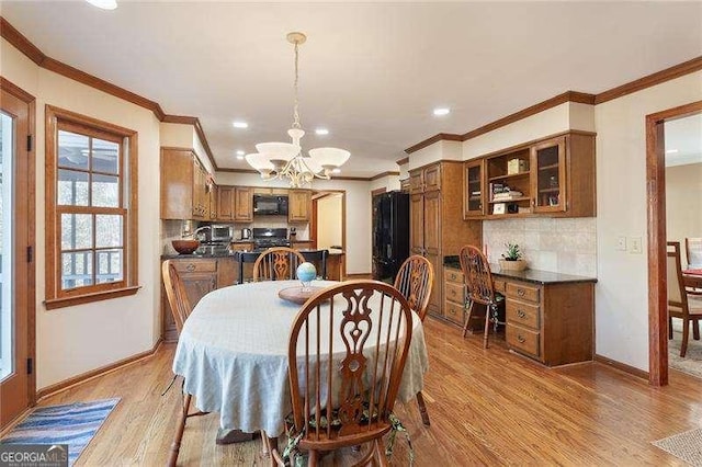 dining space with a notable chandelier, ornamental molding, and light hardwood / wood-style flooring