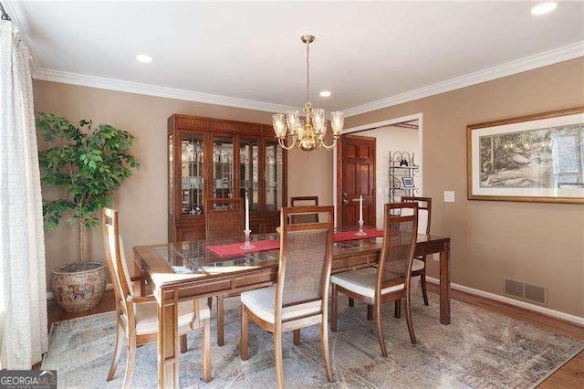 dining room with hardwood / wood-style flooring, a notable chandelier, and ornamental molding