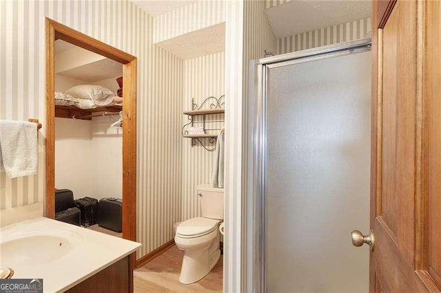 bathroom featuring vanity, toilet, wood-type flooring, and walk in shower