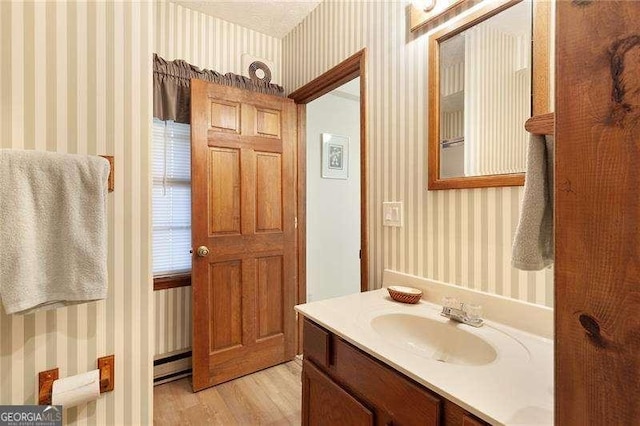 bathroom featuring hardwood / wood-style flooring, vanity, and a baseboard heating unit