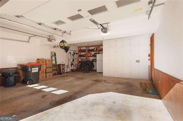 garage featuring wood walls, a garage door opener, and white refrigerator