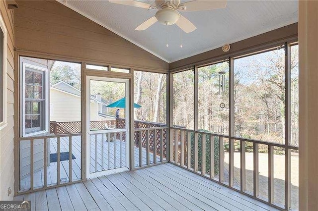 unfurnished sunroom featuring ceiling fan, a healthy amount of sunlight, and vaulted ceiling