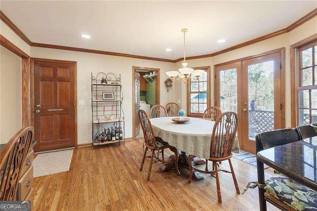 dining room with a chandelier, hardwood / wood-style floors, french doors, and ornamental molding