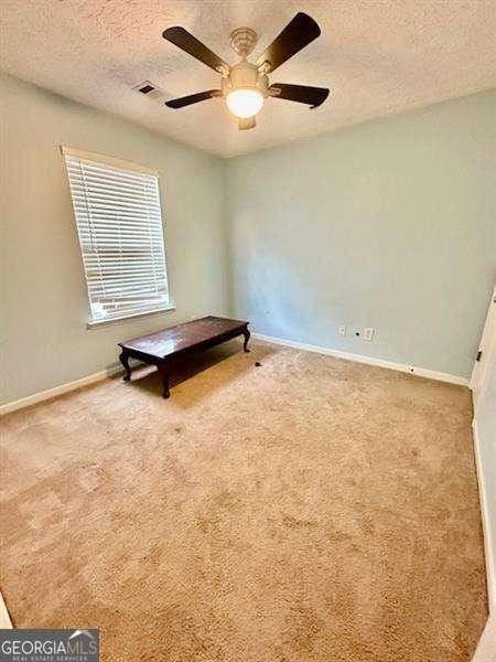 unfurnished bedroom with carpet flooring, ceiling fan, and a textured ceiling