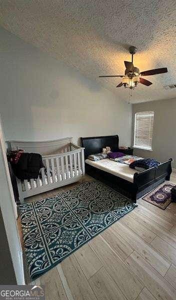 bedroom with a textured ceiling and ceiling fan