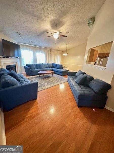 living room featuring ceiling fan, hardwood / wood-style floors, and a textured ceiling