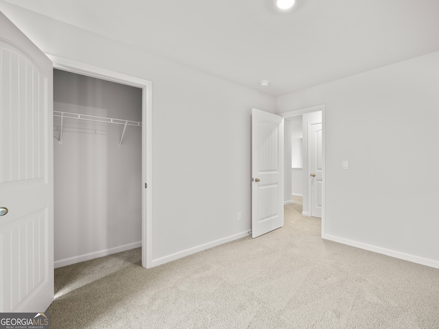 unfurnished bedroom with light colored carpet and a closet