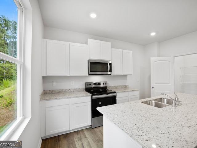 kitchen with white cabinets, stainless steel appliances, light stone countertops, and sink