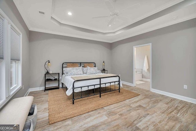 bedroom with a tray ceiling, ceiling fan, ensuite bathroom, and ornamental molding