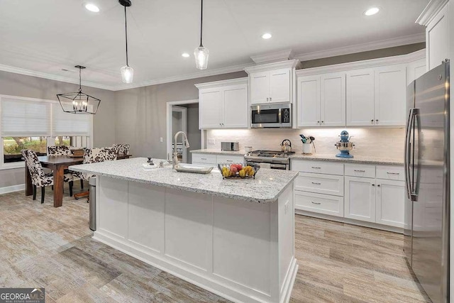 kitchen with pendant lighting, white cabinets, a kitchen island with sink, and appliances with stainless steel finishes