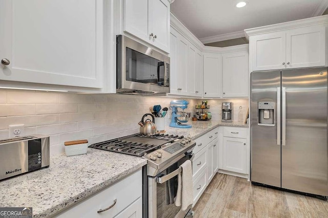 kitchen with light stone countertops, white cabinetry, and stainless steel appliances