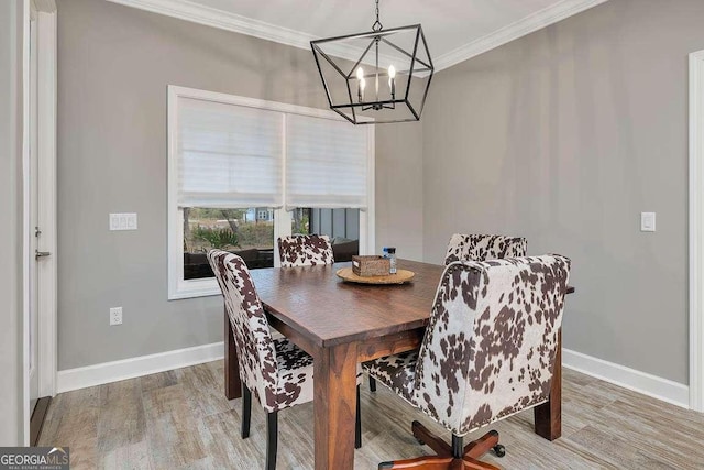 dining area featuring wood-type flooring, ornamental molding, and a notable chandelier